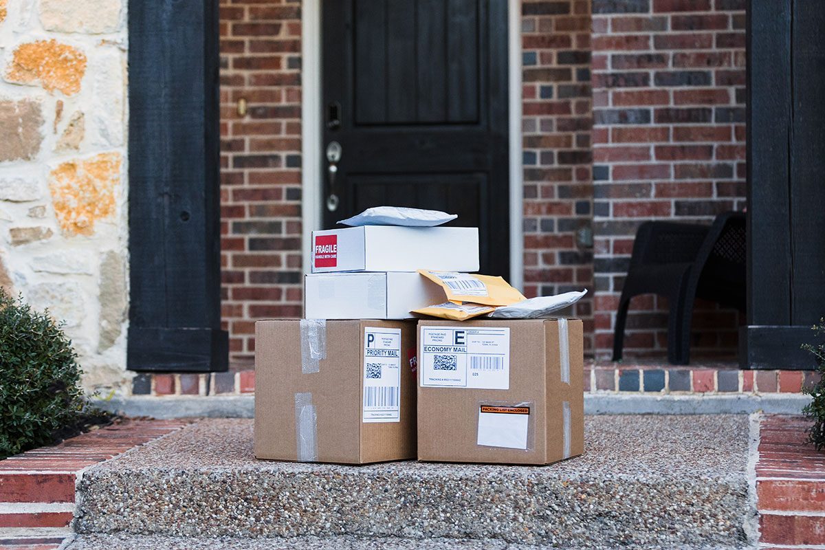 A stack of packages ready for shipping are on the front walkway of the house.
