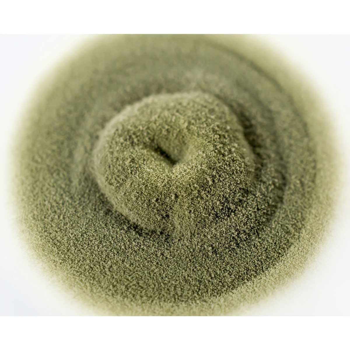 A circular mound of fine green powder is formed, resting on a smooth surface, creating a soft gradient around its edges.
