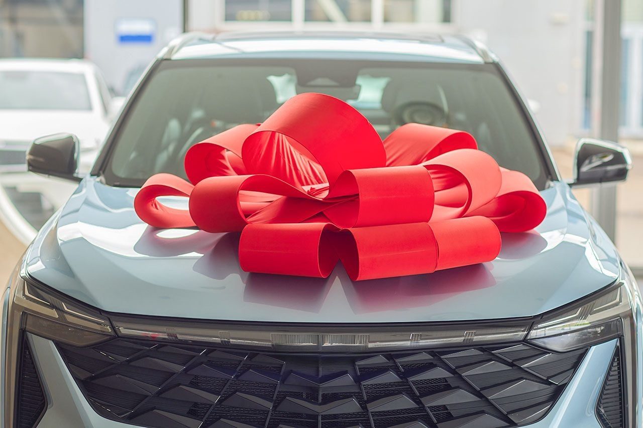 The new car is wrapped in a red bow. Beautiful gift concept.