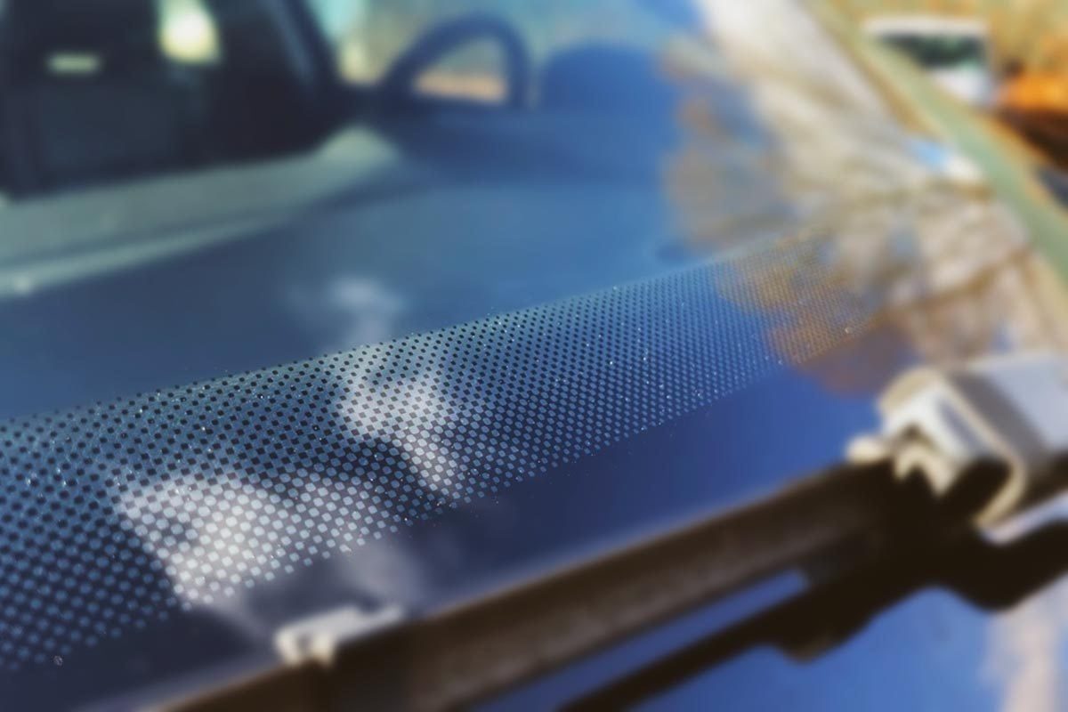 Bottom of a car windshield with a band of small black dots in focus