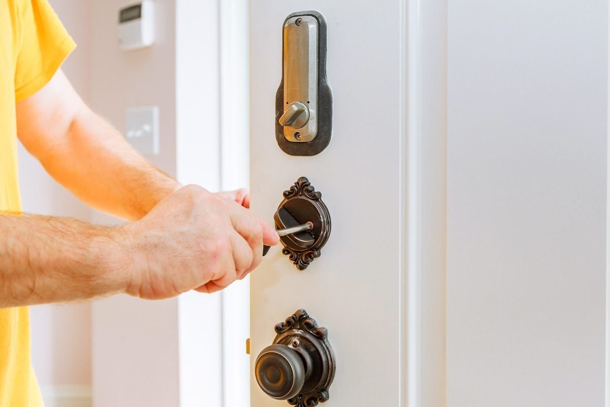 Closeup of a professional locksmith installing or repairing a new deadbolt lock on a house door with the inside internal parts of the lock v