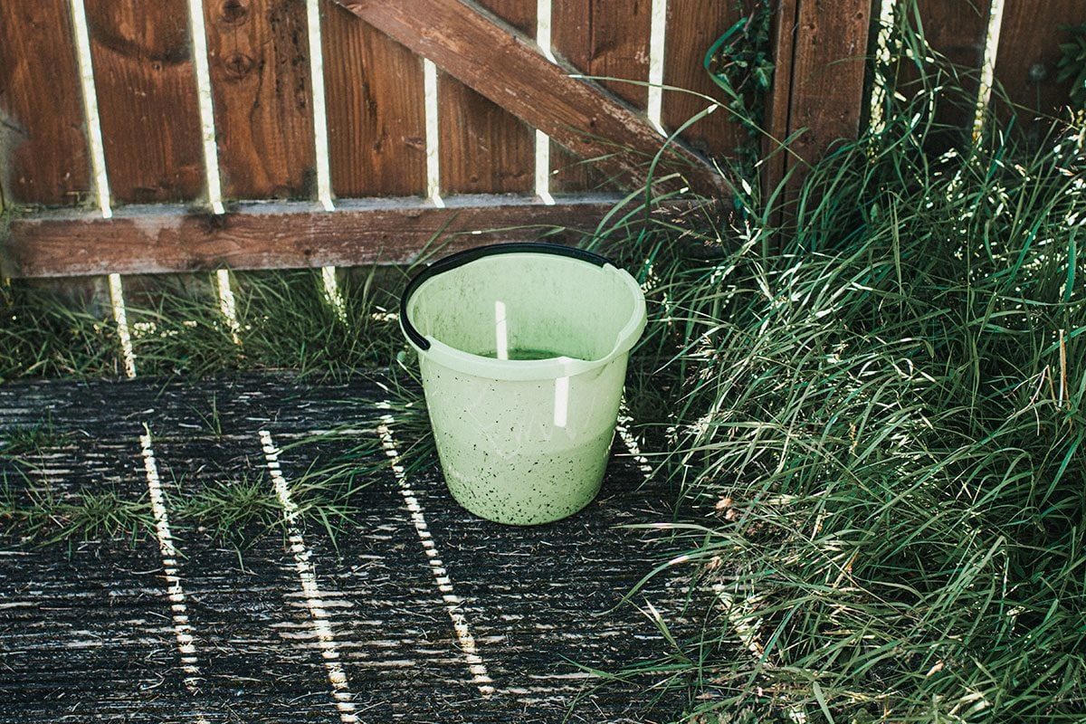 Faded Green Bucket sitting on Wooden Decking in Sunbeams