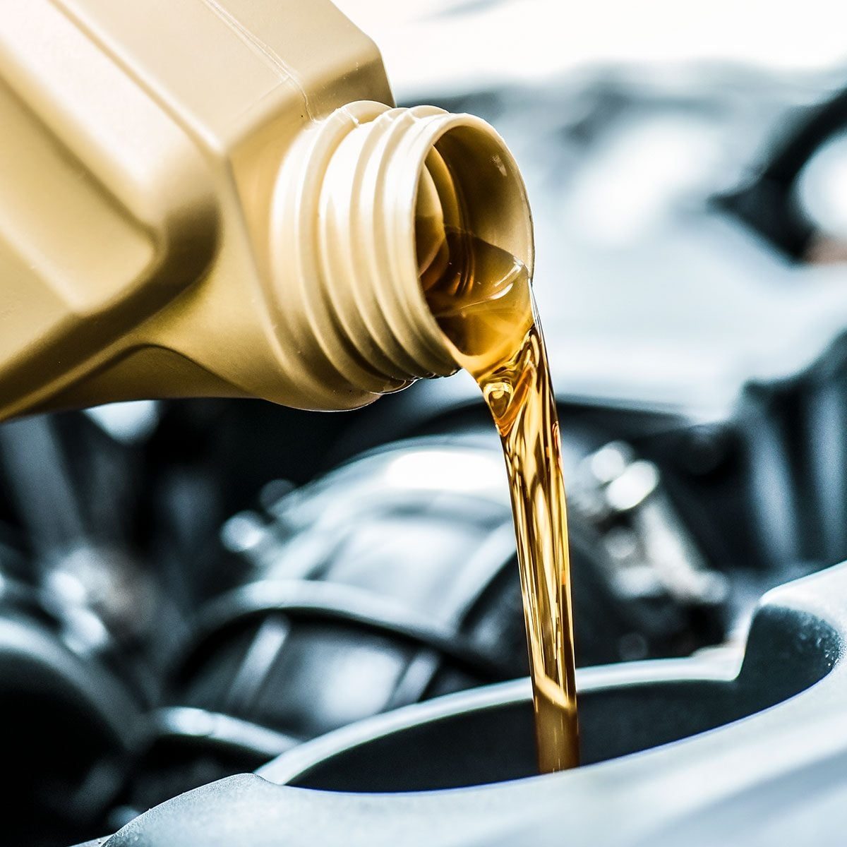 Pouring motor oil from plastic canister in car repair service center