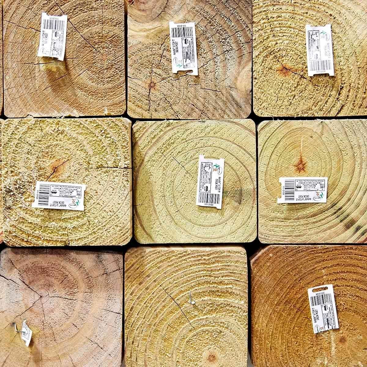 Nine wooden blocks are arranged in a grid, each displaying circular growth rings and adhesive price tags on top, set against a neutral backg