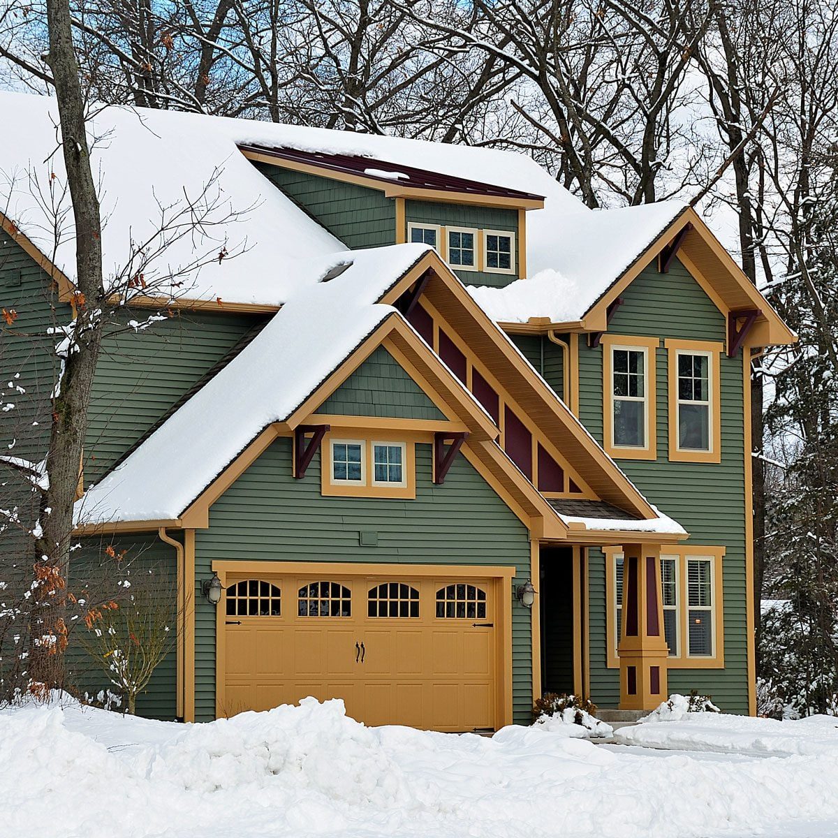 Modern green and yellow house in the winter with snow on the ground and on the roof