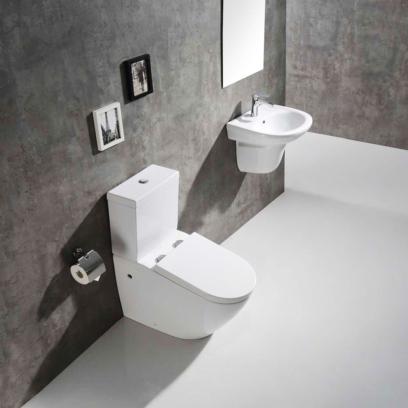 A white toilet sits on a sleek, white floor, next to a wall-mounted sink, in a minimalist bathroom with textured gray walls and framed pictu