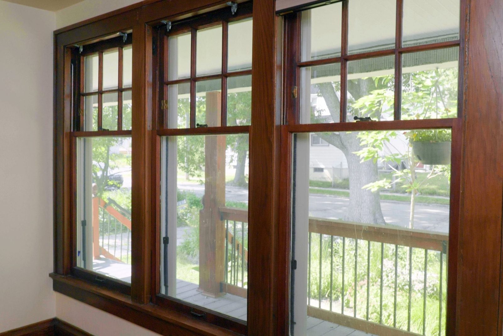Wooden window frames display a clear view of greenery and a front porch, while sunlight brightens the interior space.