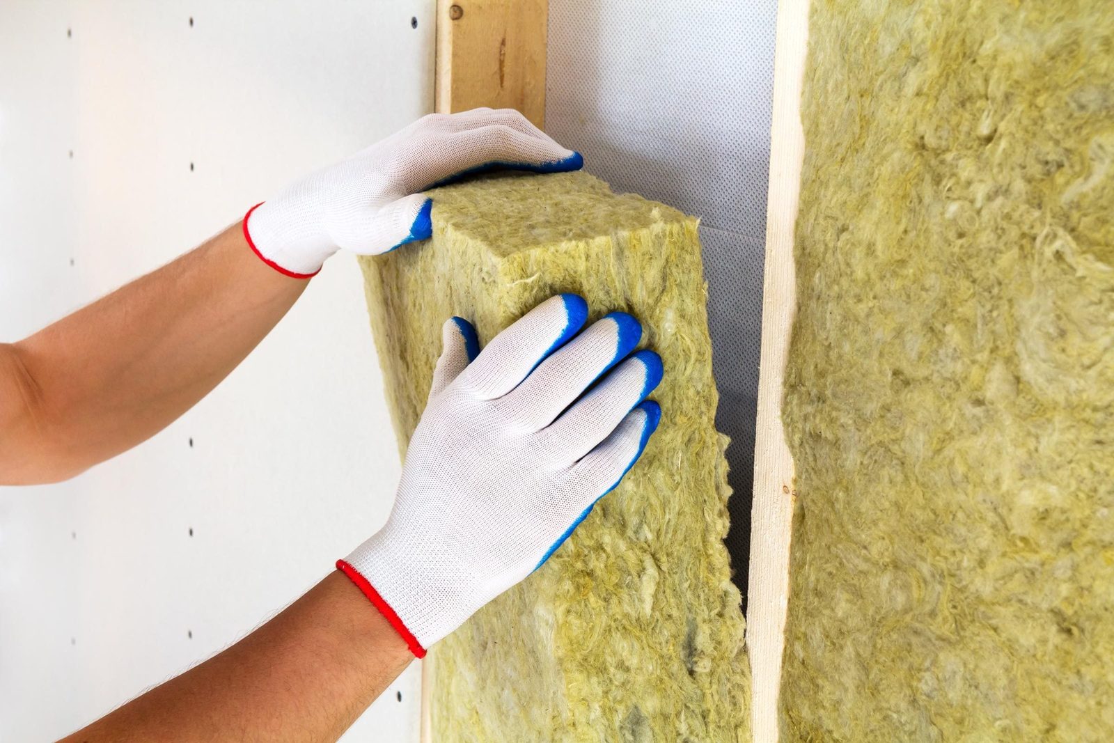 Close-up of worker hands in white gloves insulating rock wool insulation staff in wooden frame for future walls for cold barrier. Comfortabl