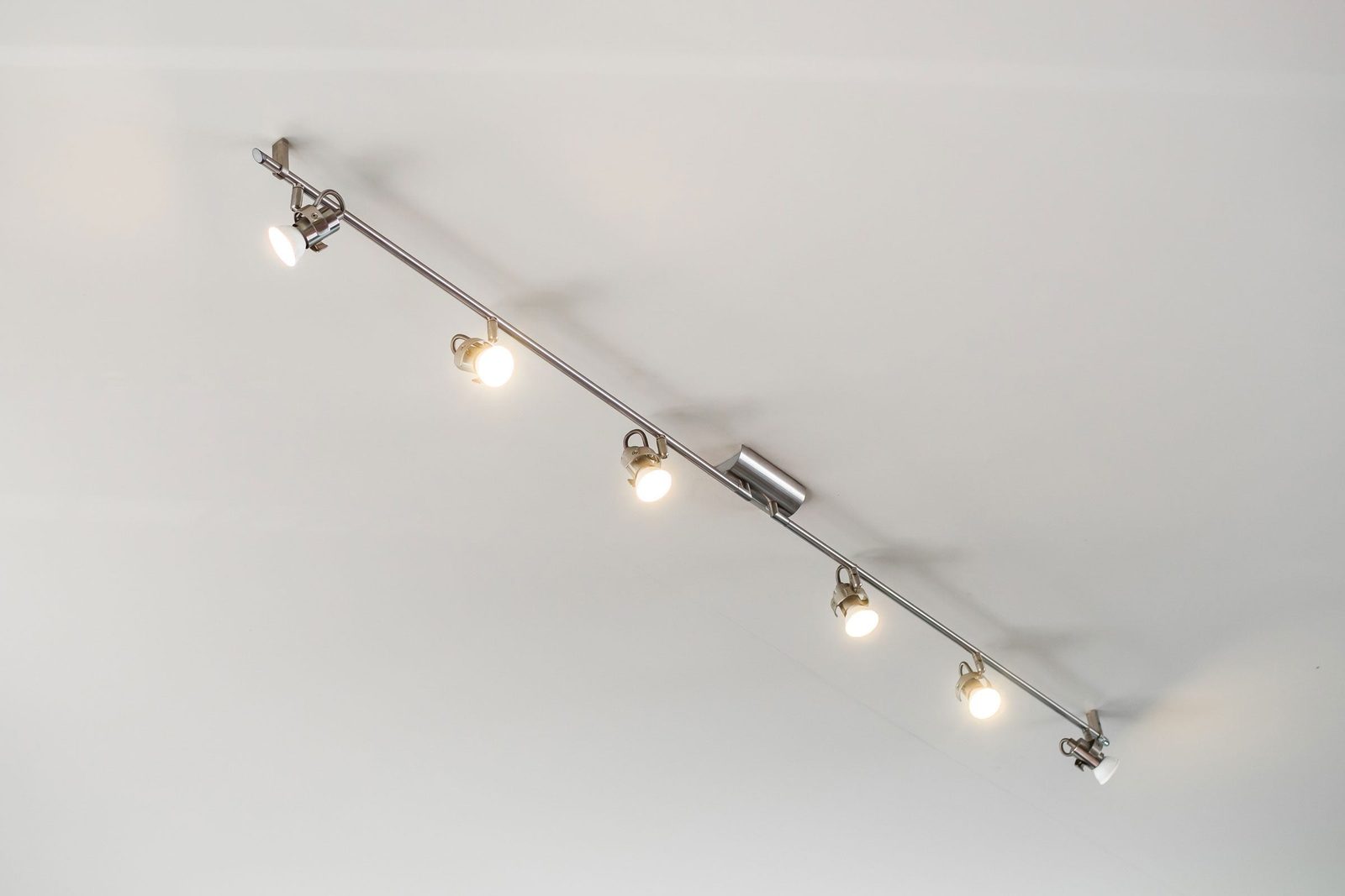 A row of six mounted spotlights illuminates a white ceiling, suggesting a modern interior lighting setup.