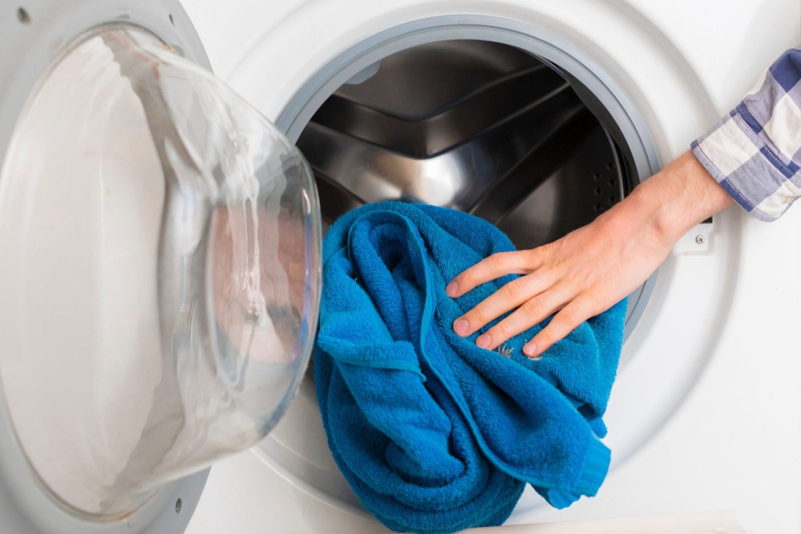 persons hand put dirty clothes in the washing machine b