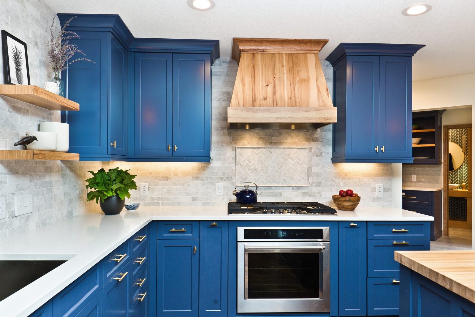 Blue kitchen cabinets with a modern design complement a white countertop and stainless steel appliances, illuminated by warm lighting agains