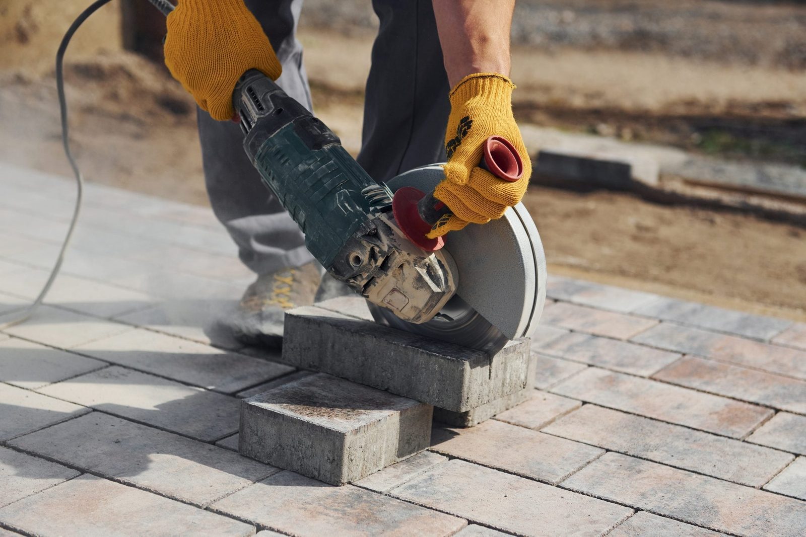 Uses circular saw. Male worker in yellow colored uniform have job with pavement