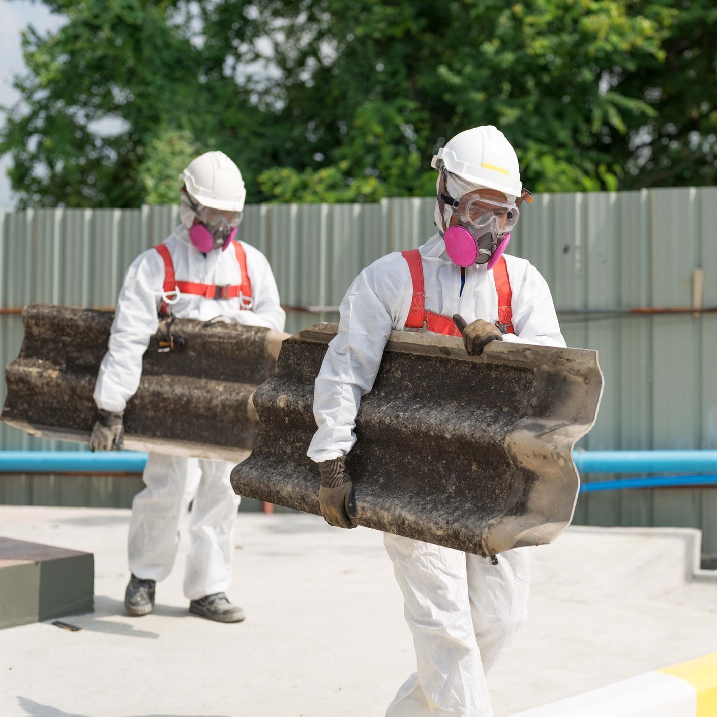 Safety is our top priority. Workers wearing full body protective clothing while working with the asbestos roof tiles.