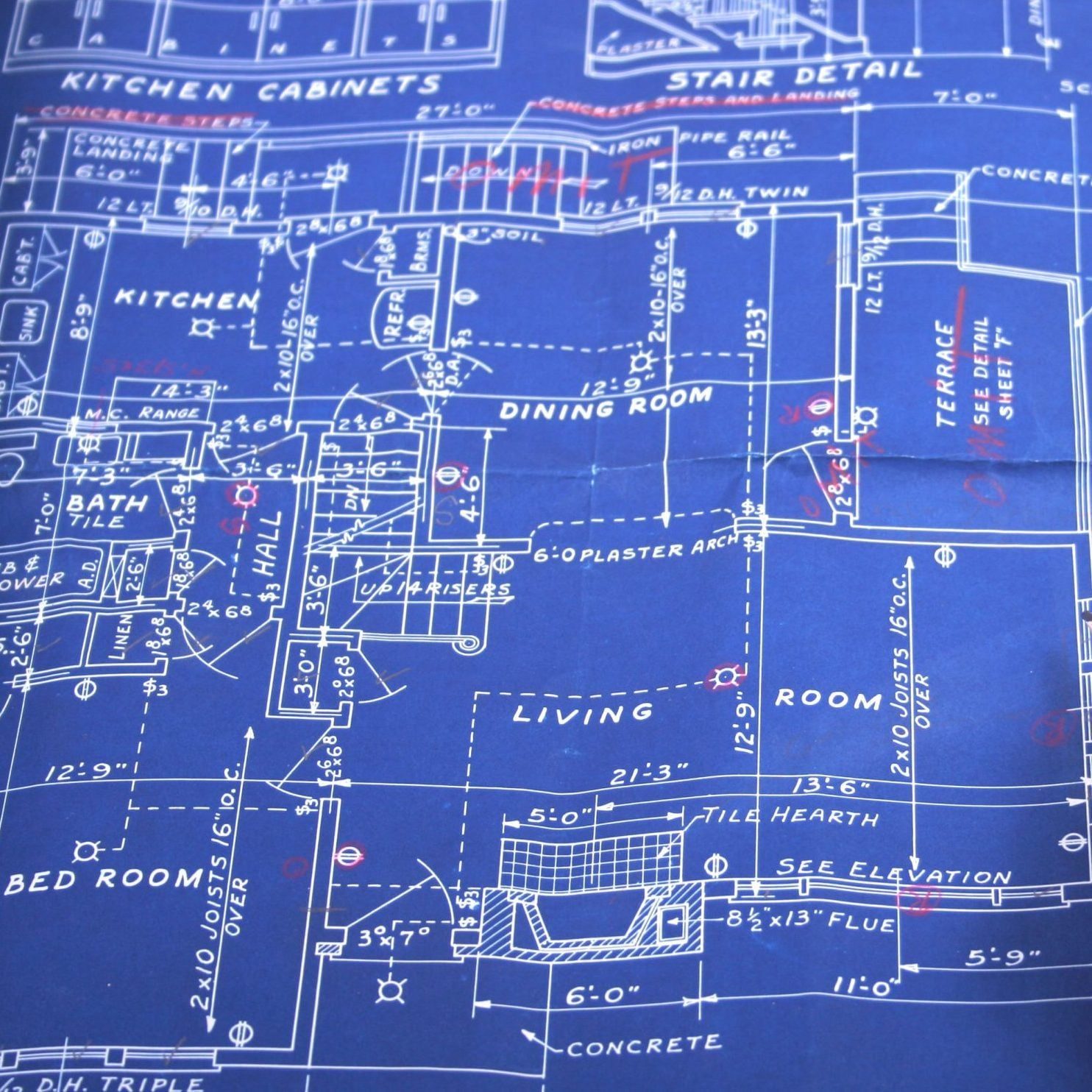 Blueprint of a house layout, detailing rooms like kitchen, dining room, and living room, with measurements and annotations marked in red on