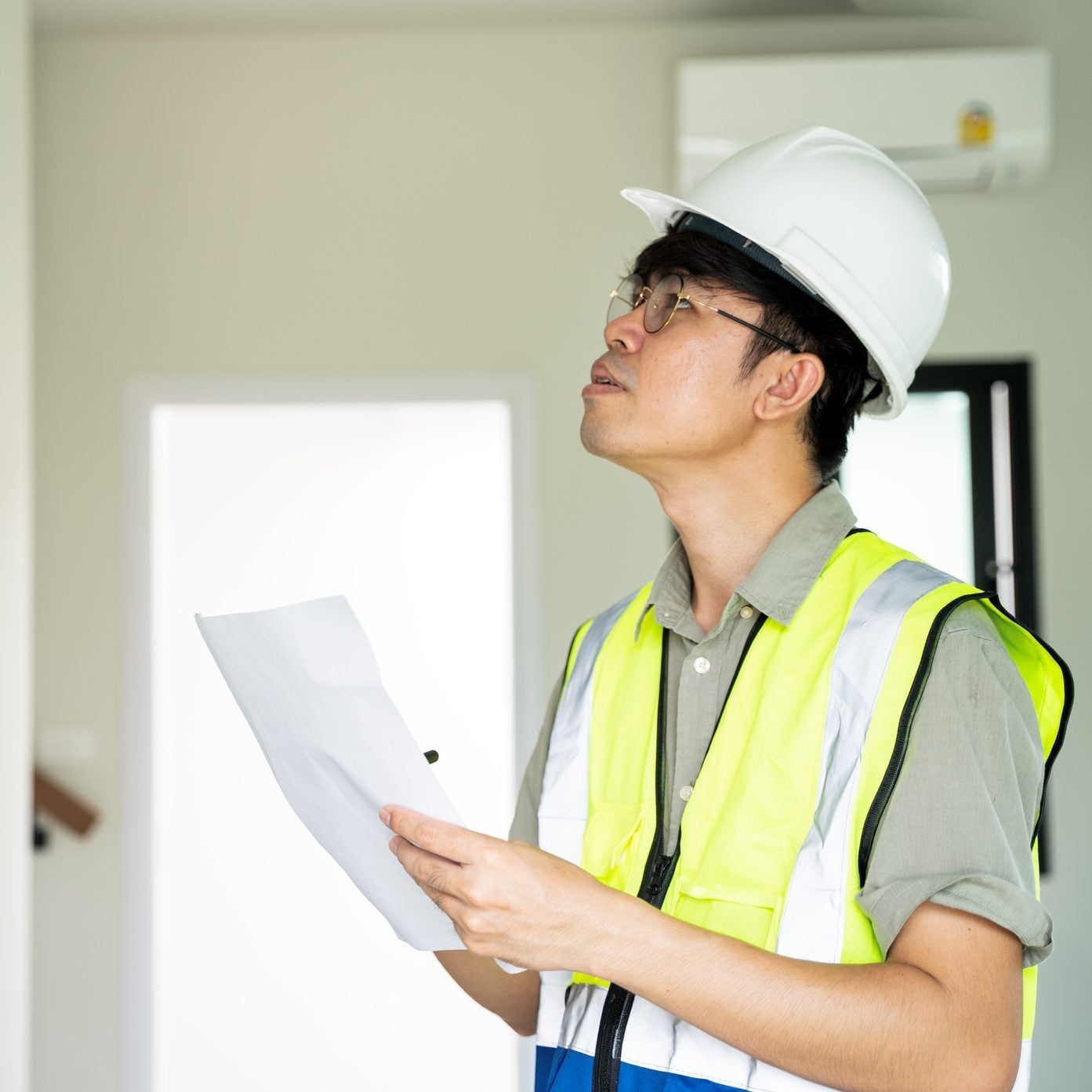 Inspector with tablet and helmet looking at ceiling in house