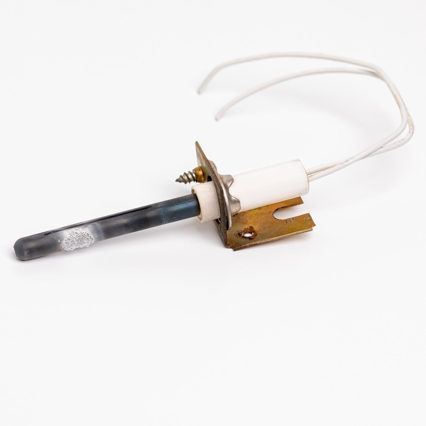 A metal heating element with a ceramic base and wires protrudes, resting on a plain white surface, suggesting it may be used for heating or