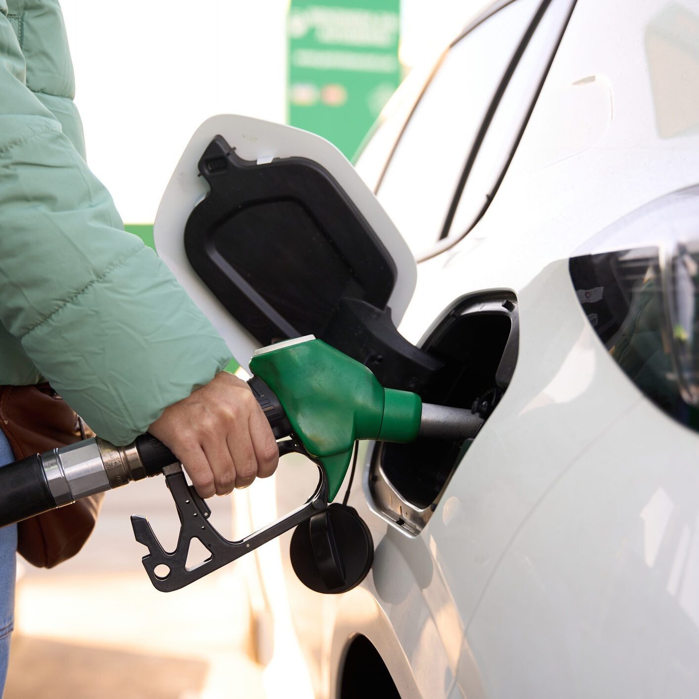 close-up of a woman hand fueling tank of car with a green diesel pump
