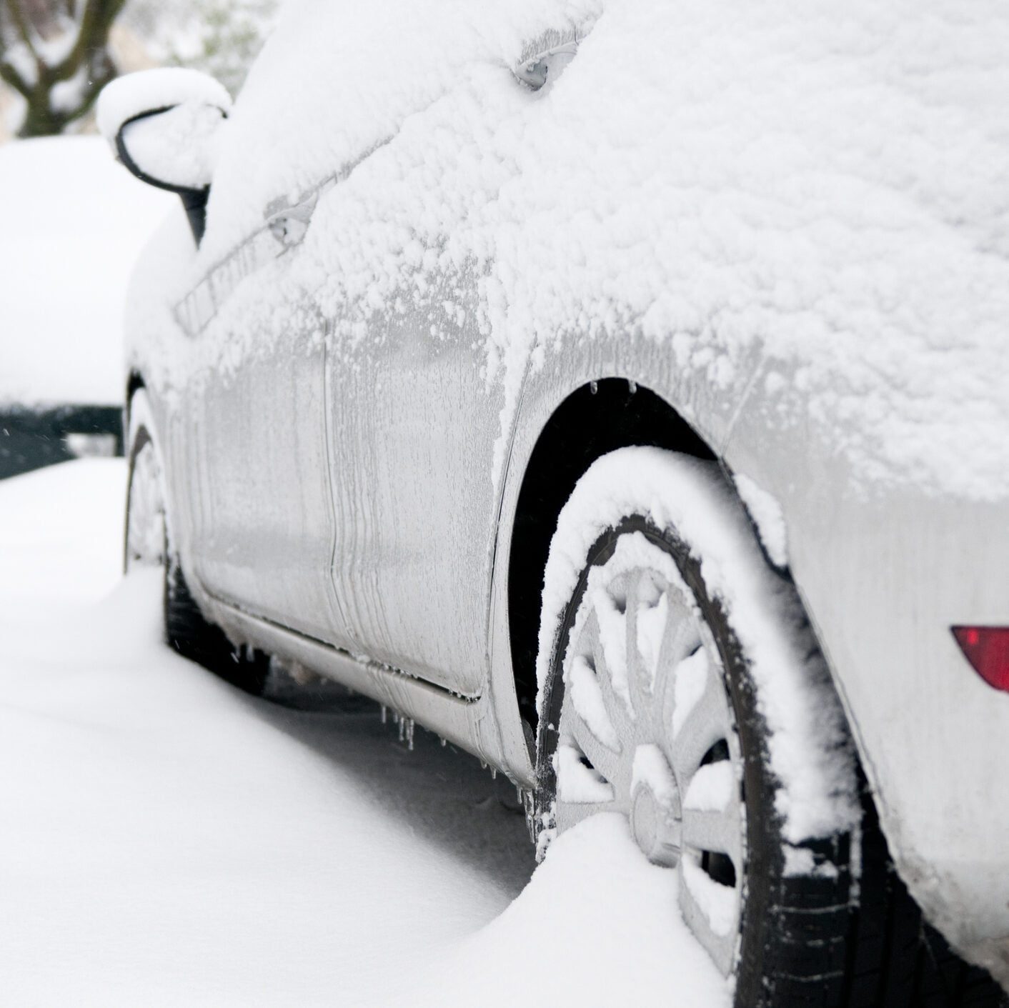 Snow-covered gray car with its wheels stuck in snow