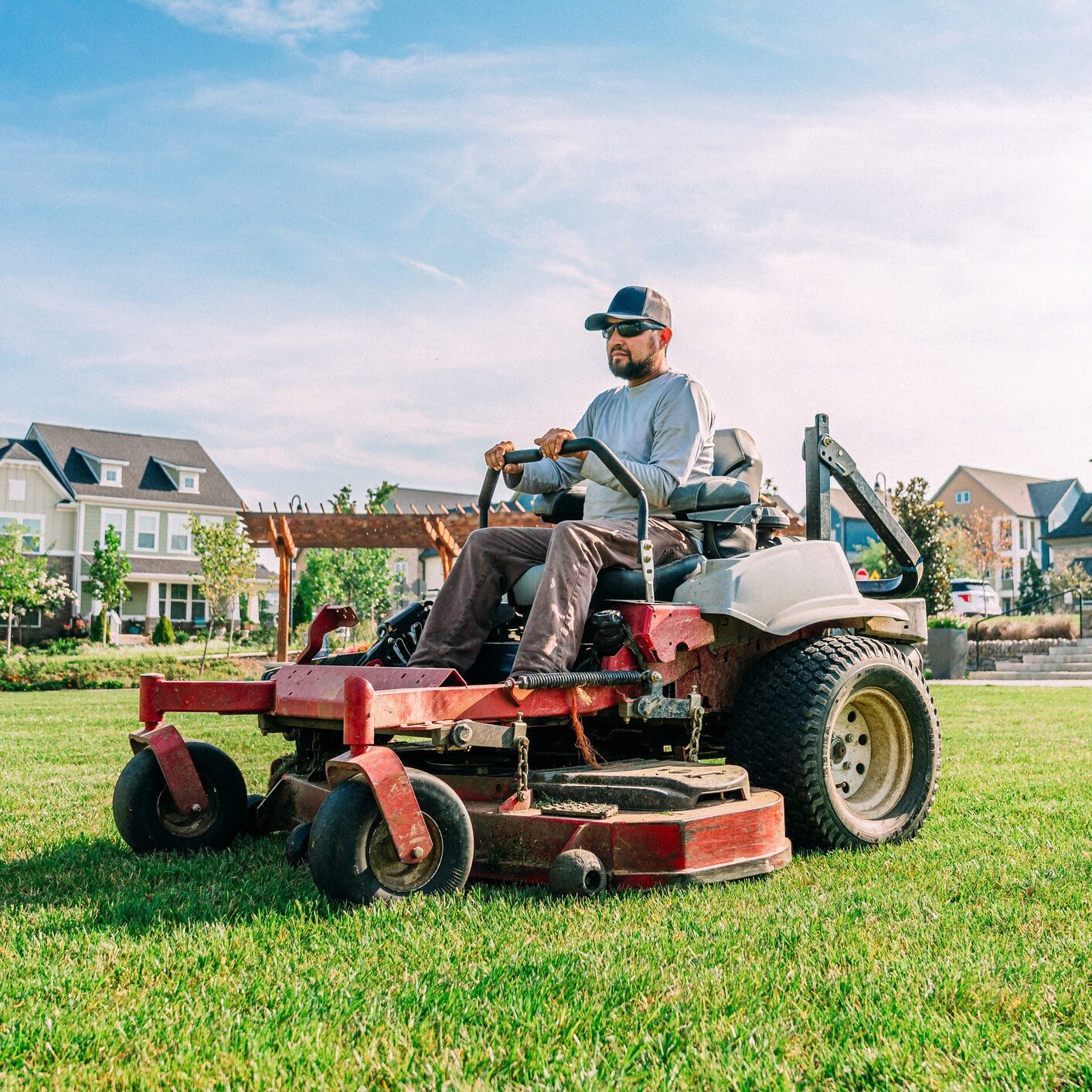Man driving a lawn mower on a residential patch of grass