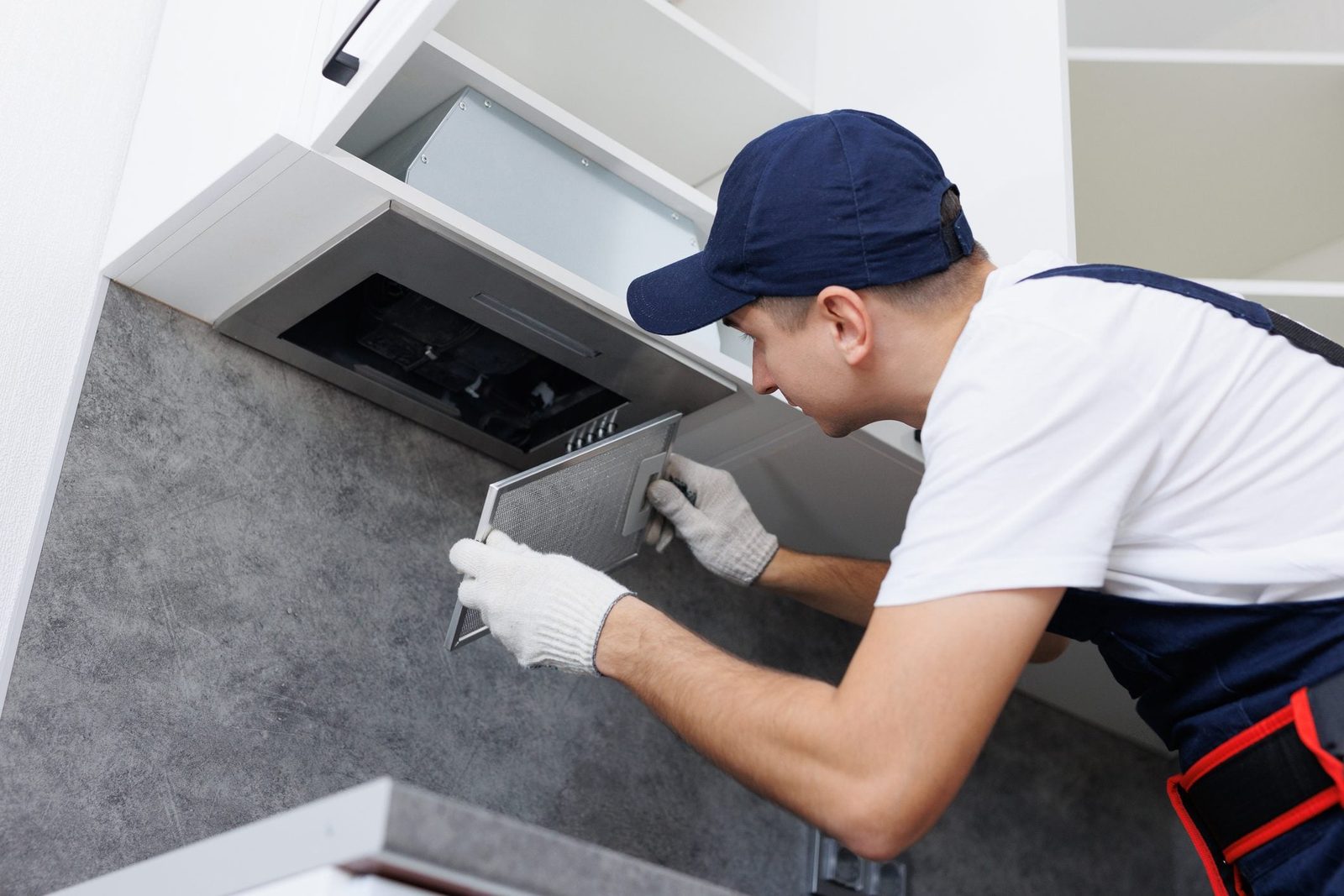 Man removing a filter from cooker hood for cleaning. Replacing filter in kitchen hood.