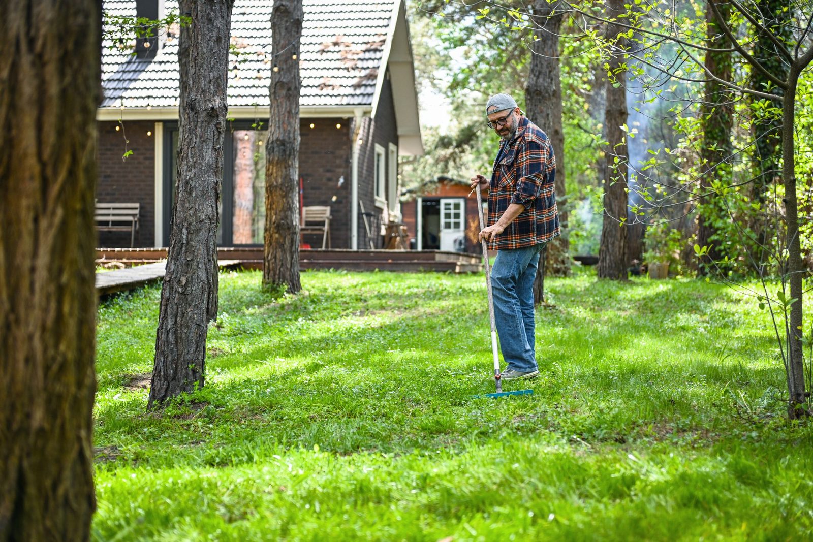 A mature adult man cleans the area around his country house.