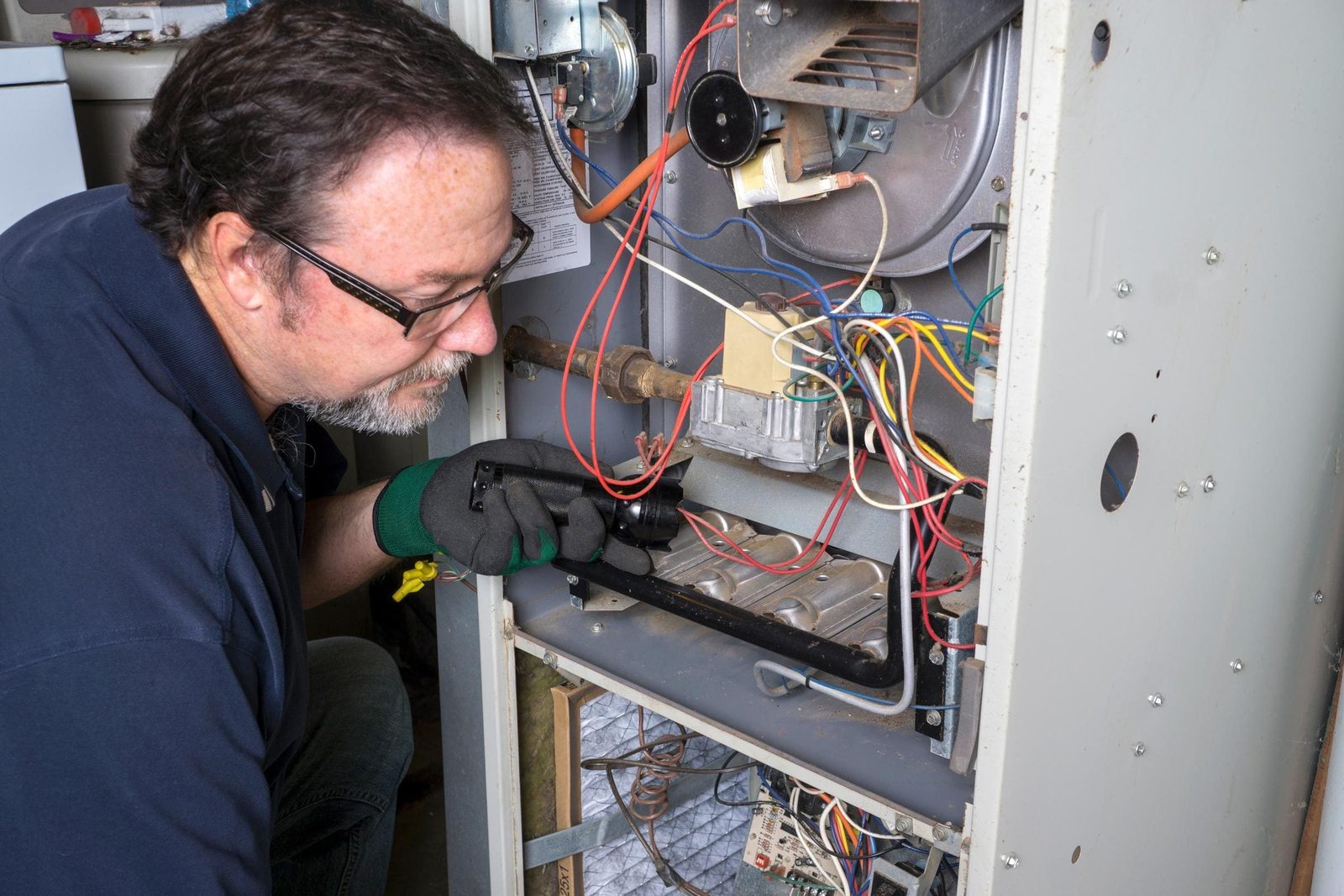 Technician Looking Over A Gas Furnace for a furnace tune-up