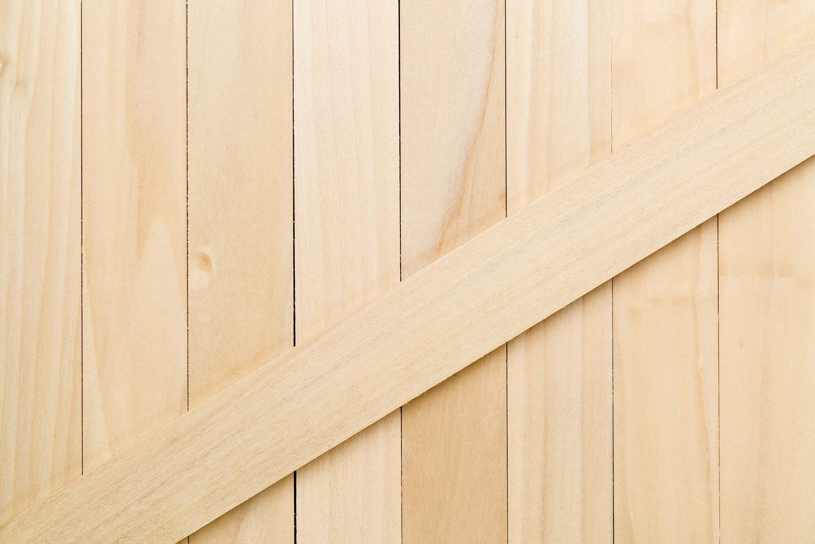 Light-colored wooden planks are arranged vertically, with a diagonal strip of wood crossing them, creating a simple, minimalistic surface.