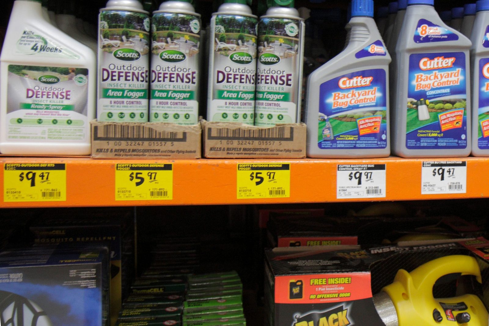 Bottles and cans of insect repellents are displayed on a shelf in a store, showcasing various products and prices for outdoor pest control s