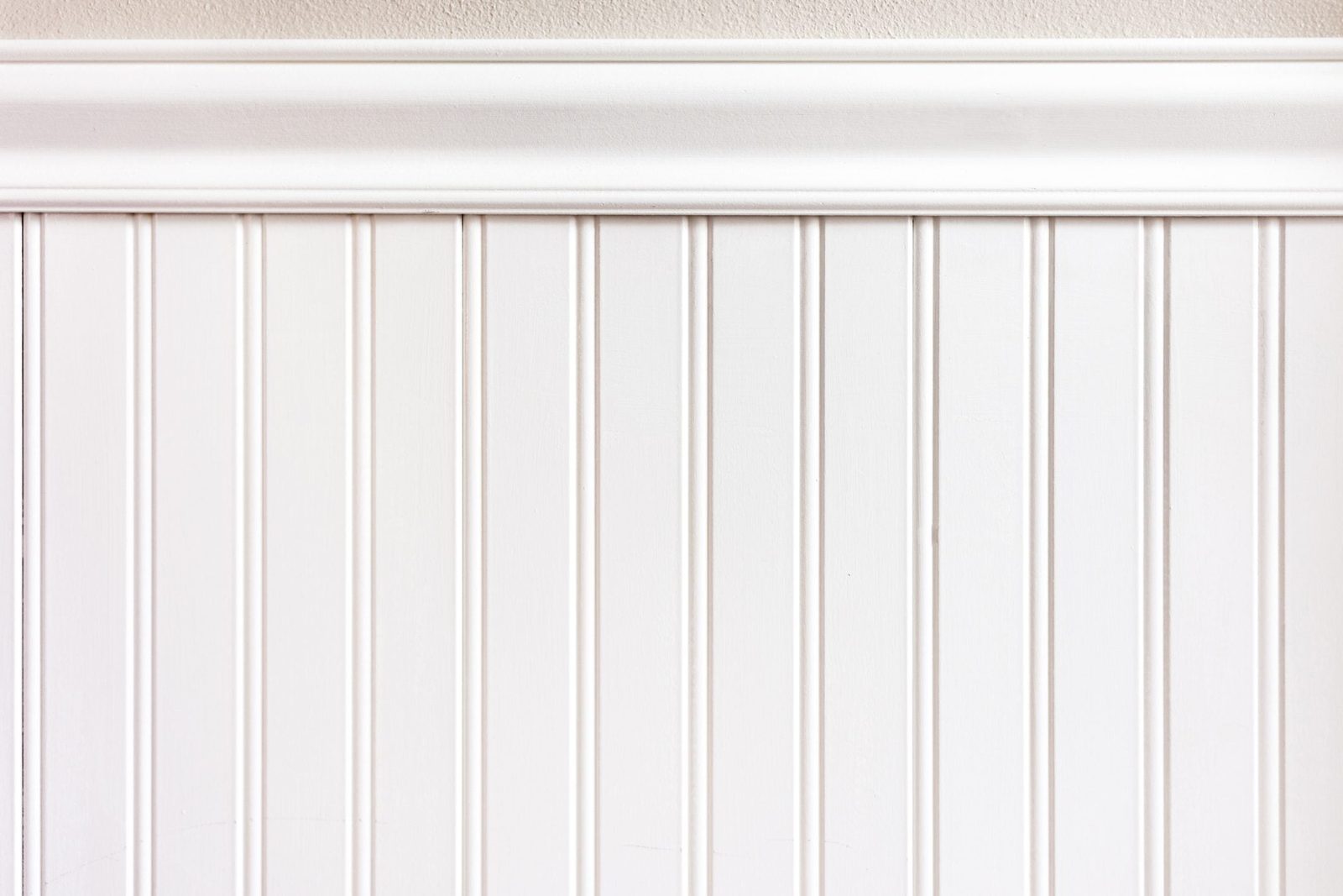 A white paneled wall features vertical grooves, topped with a decorative white molding, creating a clean and simple interior aesthetic.