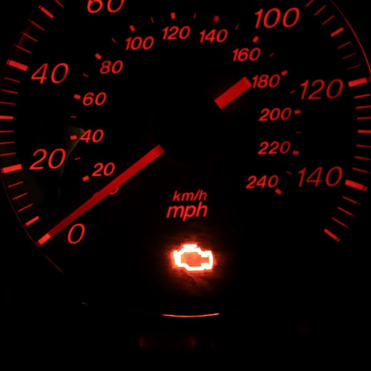 A vehicle speedometer displays a red check engine light, indicating a potential issue. The surrounding environment is dark, enhancing the gl