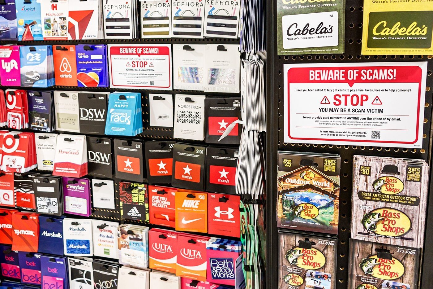 A gift card stand displays scam warning.