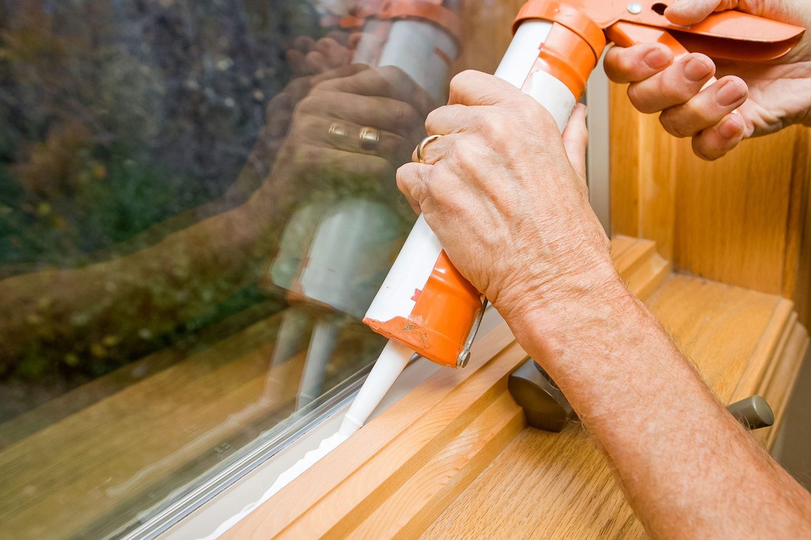 Hands Applying Weather Seal Caulk To Window Frame