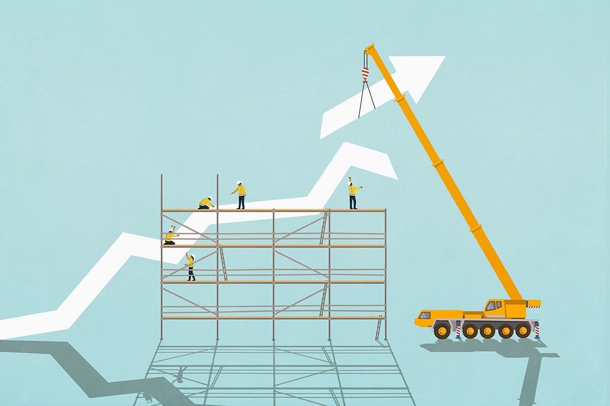 Construction workers on scaffolding below crane assembling ascending graph arrow