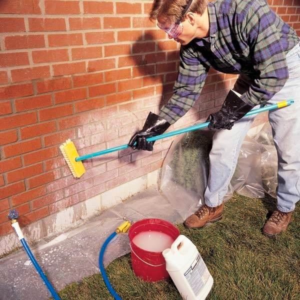man scrubbing efflorescence off of brick