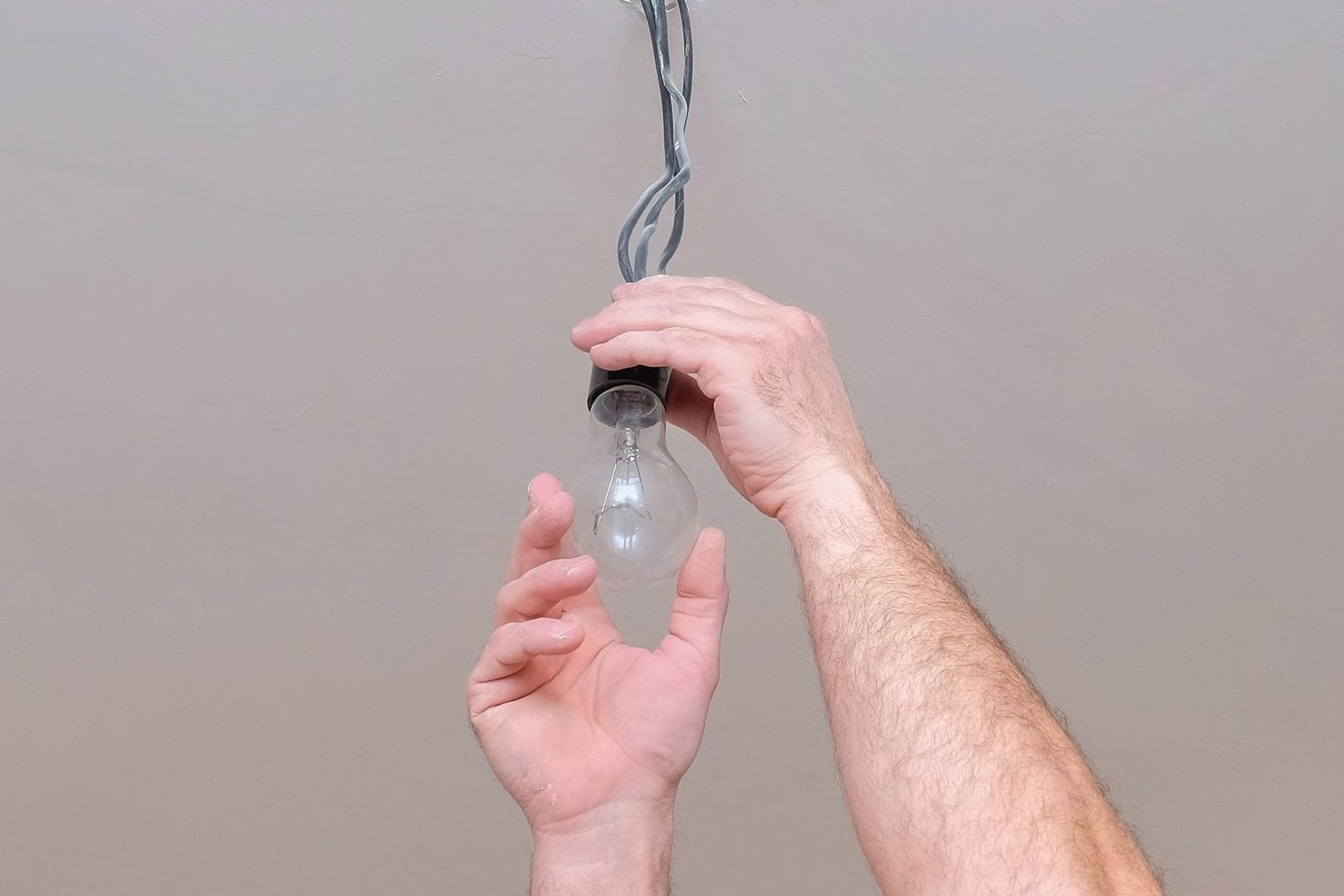 Hands can be seen unscrewing a lightbulb.