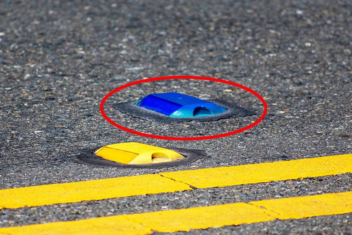 Raised yellow pavement marker separates opposing traffic lanes. The blue marker denotes a fire hydrant location