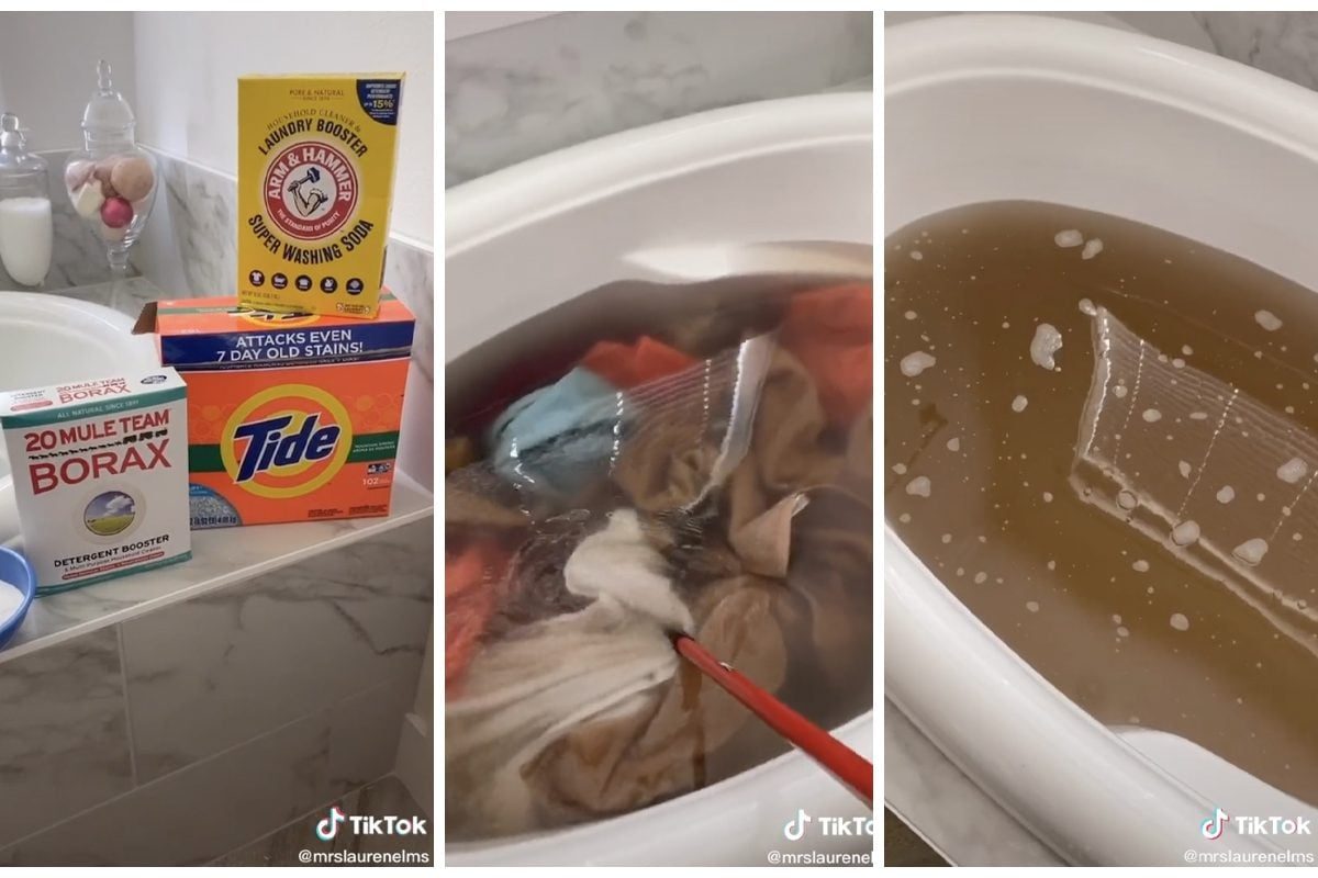Laundry detergents and boosters are displayed beside a bathtub filled with water and stained clothes, as someone stirs the mixture with a re