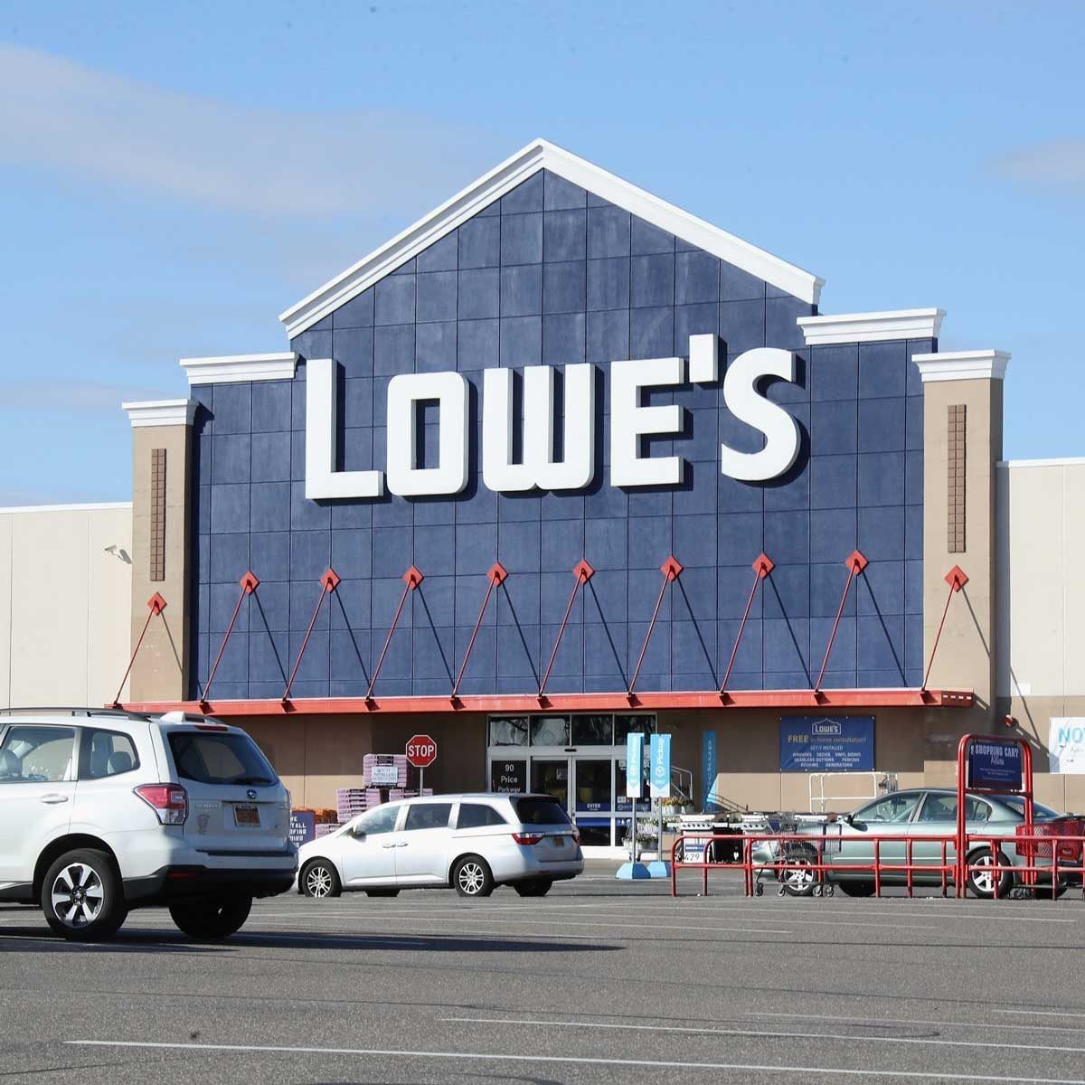 A large retail building displays the "Lowe's" sign, while vehicles park in front. The sky is clear, indicating a bright day.