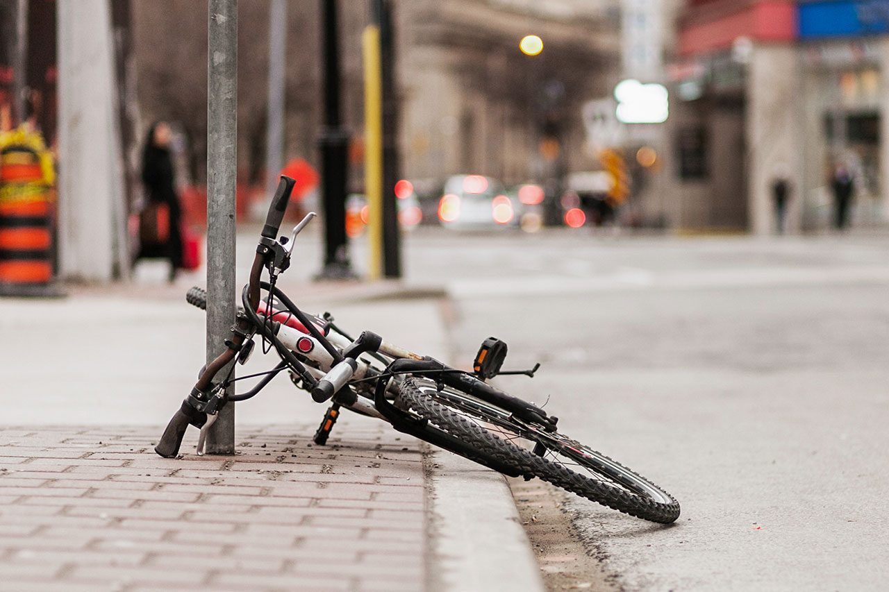 A bicycle has been chained to a post but not in a proper way
