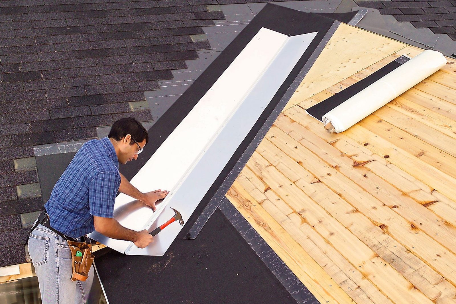 A man can be seen installing valley flashing on a roof