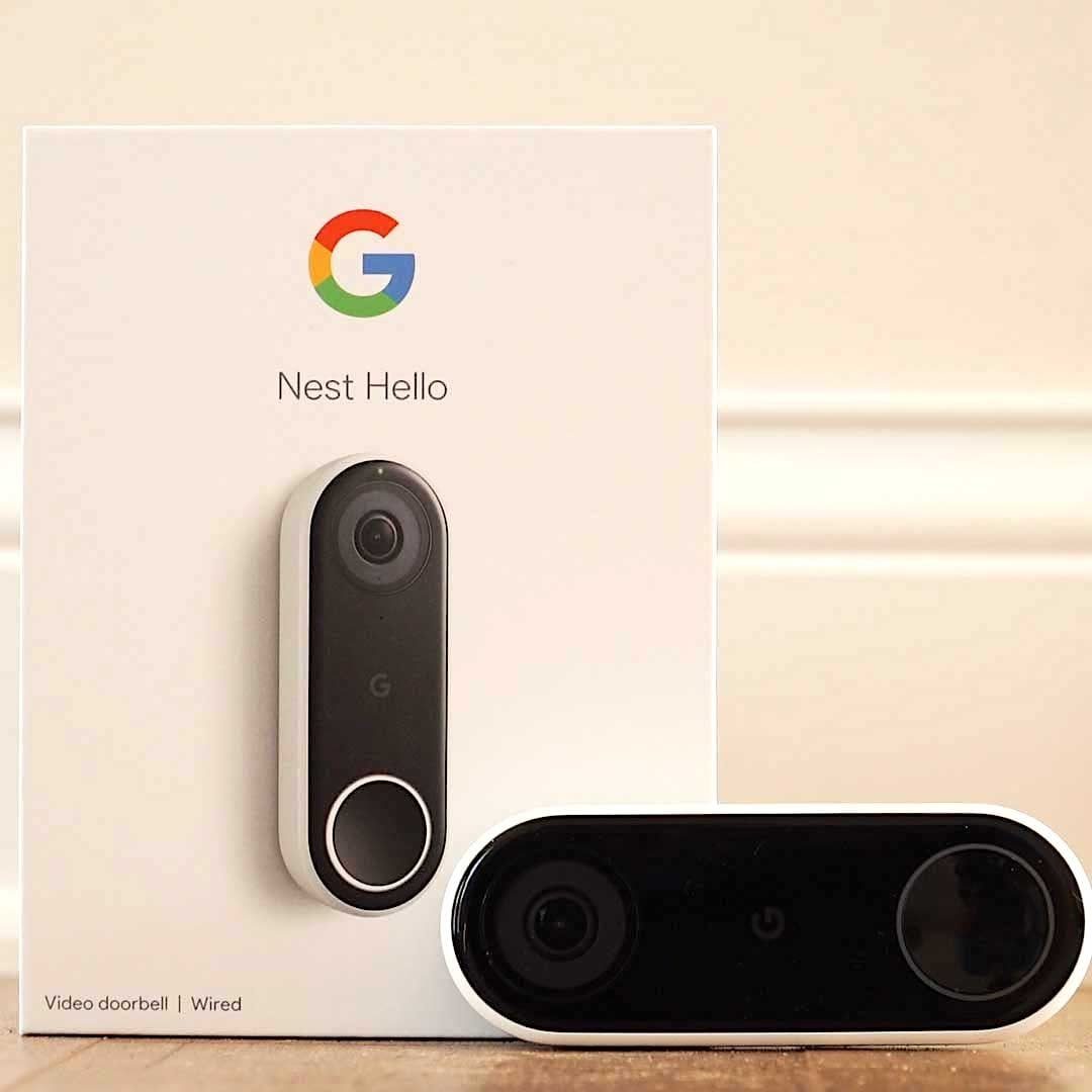 A video doorbell sits beside its box, displaying "Nest Hello." The doorbell is black and white, placed on a neutral surface against light-co