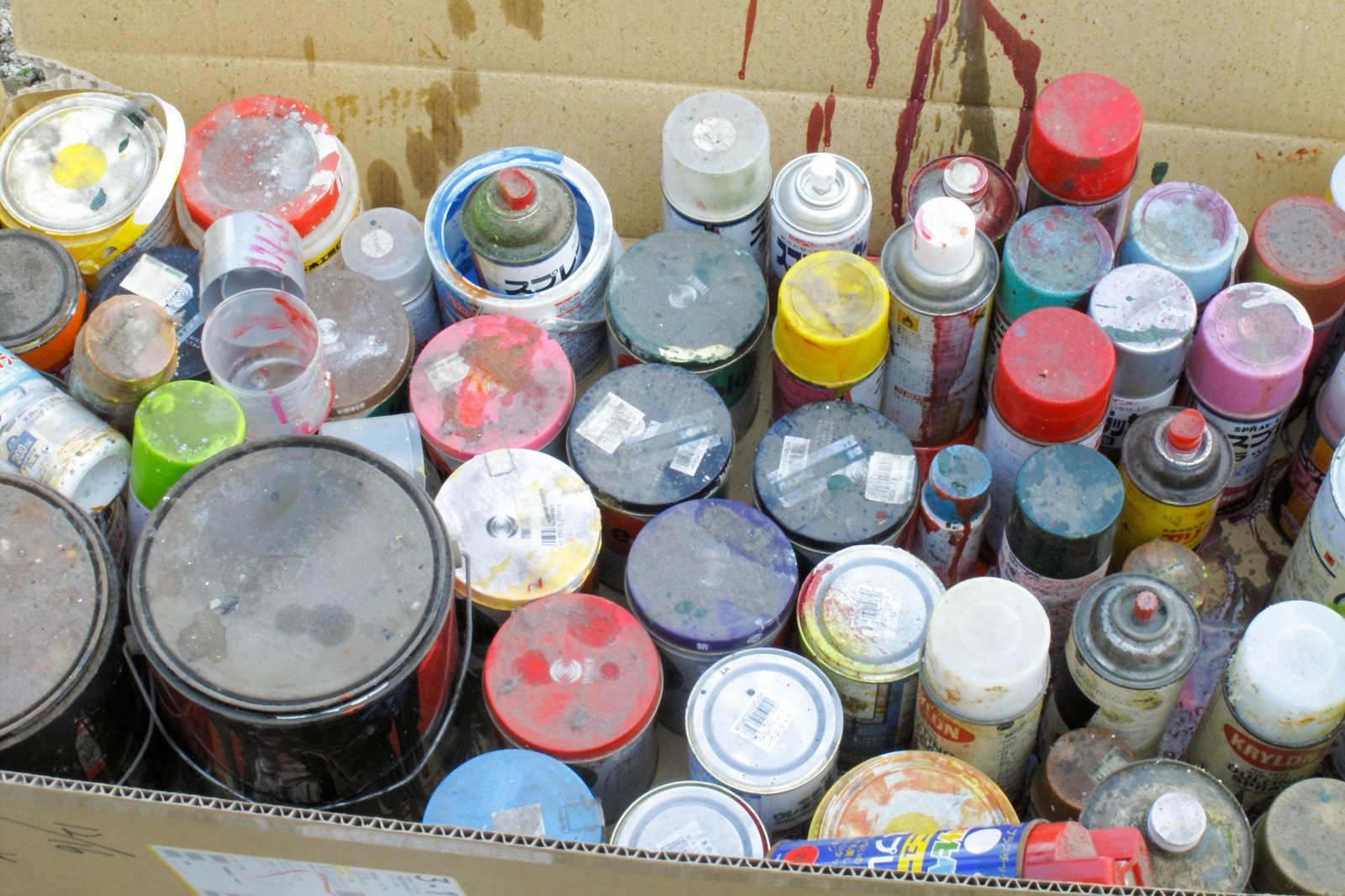 old cans various types of paint in a cardboard box