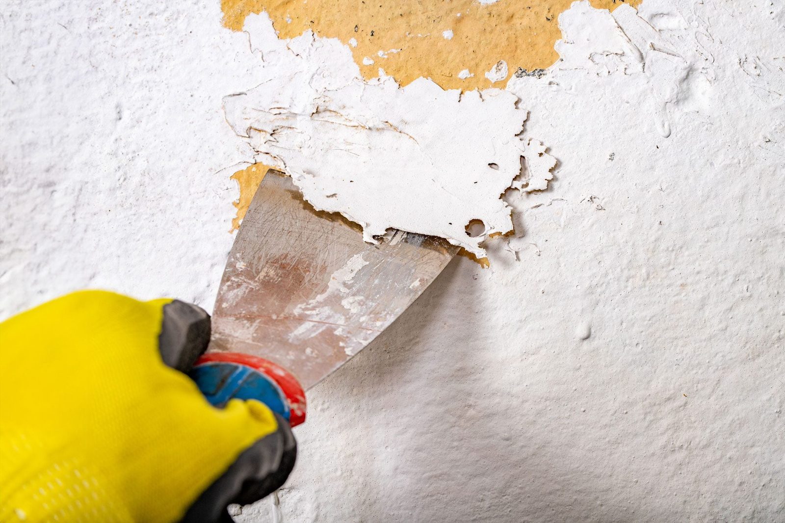 Removing Old Lead Paint From The Wall With A Metal Spatula