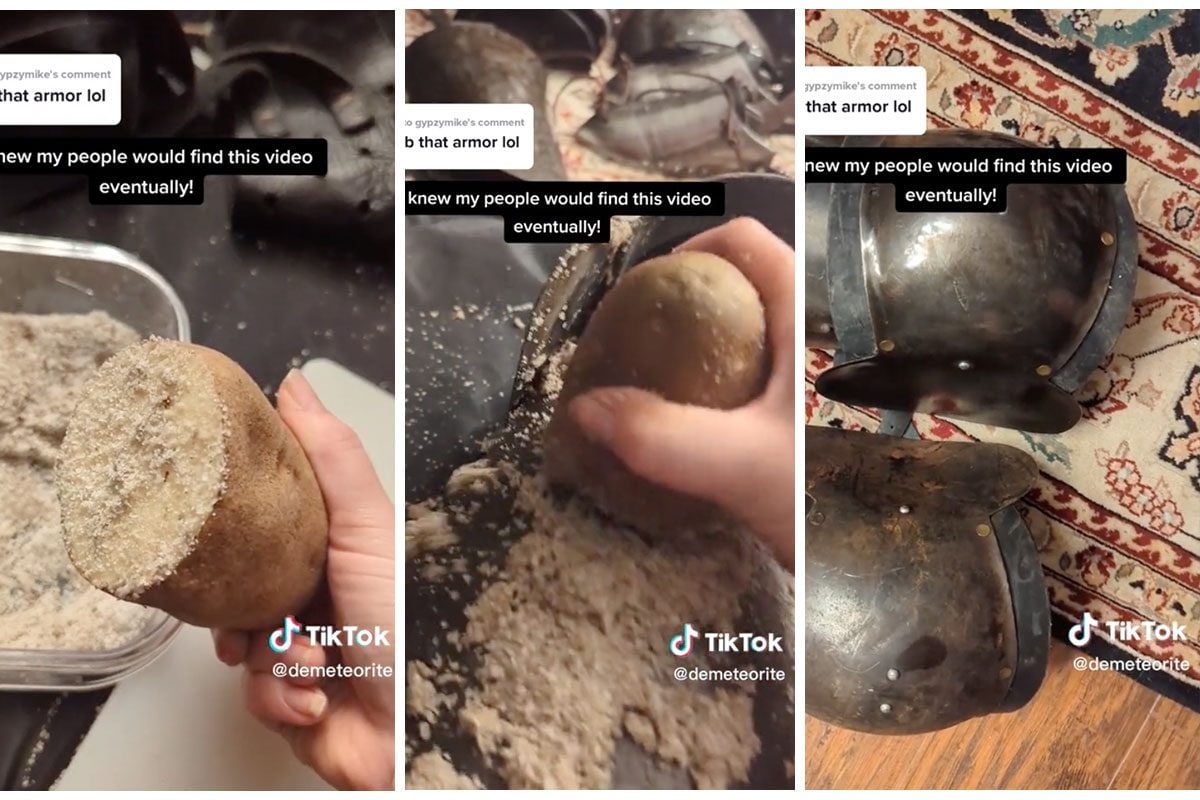 A hand holds a potato covered in sand, while ancient armor pieces rest on a patterned rug, showcasing a contrast between the objects.