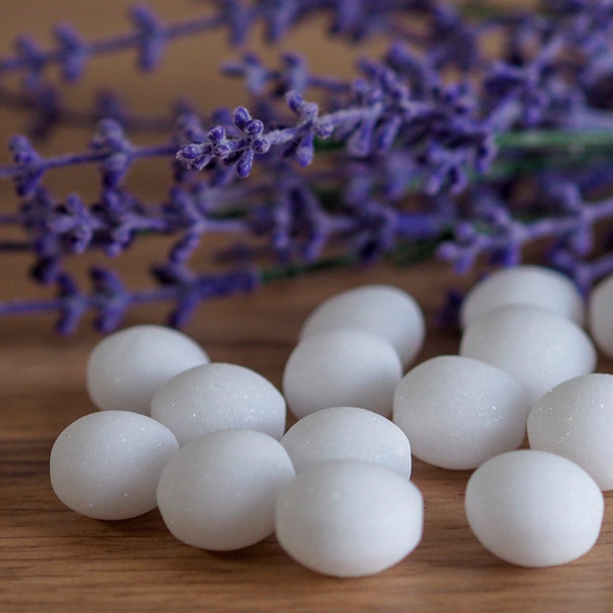 White, round objects rest on a wooden surface, surrounded by sprigs of purple lavender, creating a serene, natural arrangement.