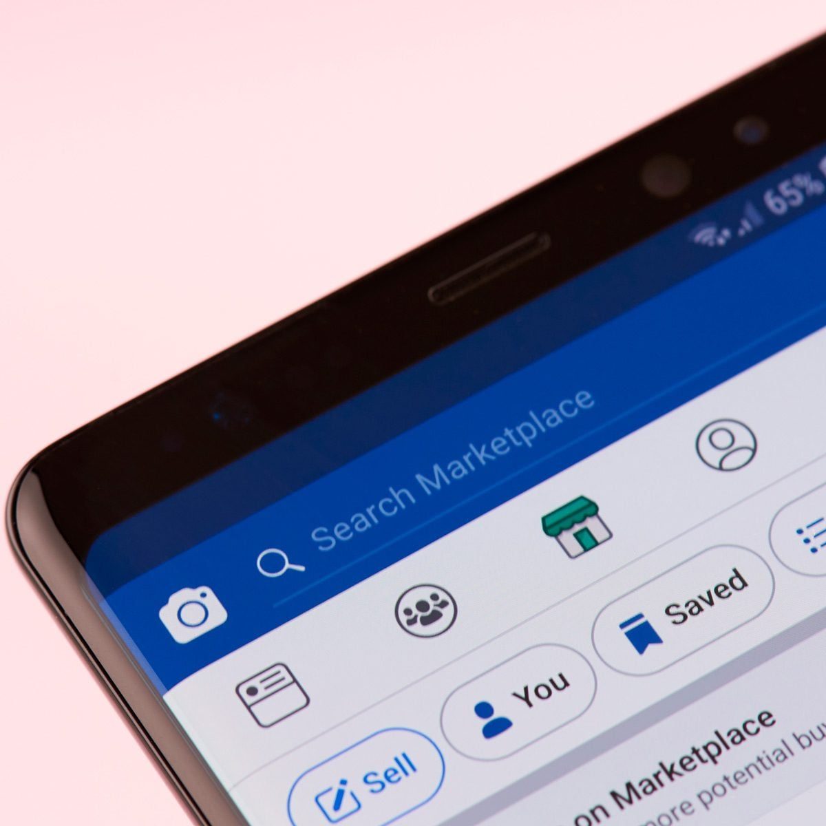 A smartphone screen displays a social media marketplace interface, featuring options to search, sell, and view saved items, against a soft p