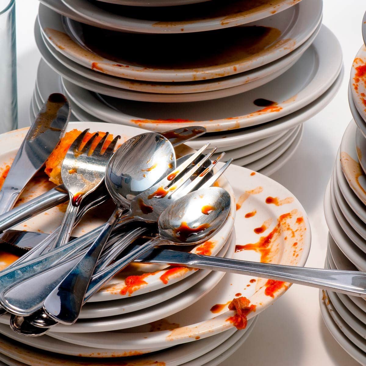 A pile of dirty plates and utensils rests precariously, smeared with remnants of food, indicating a recent meal shared in a busy dining cont