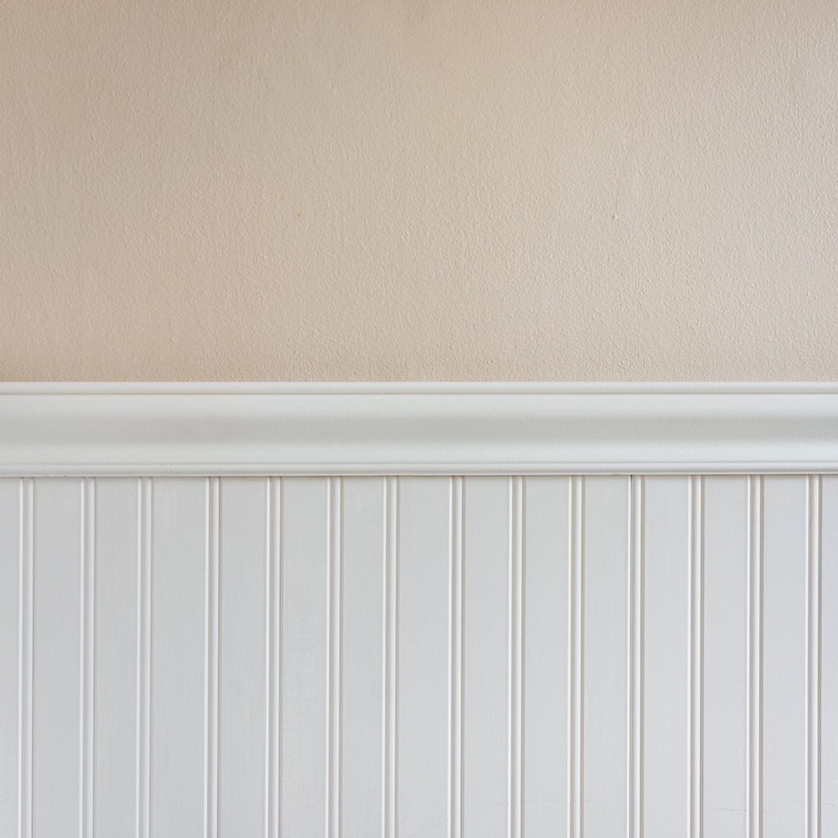 A white beadboard panel runs along the bottom, while a smooth beige wall extends above it, creating a clean, simple interior space.