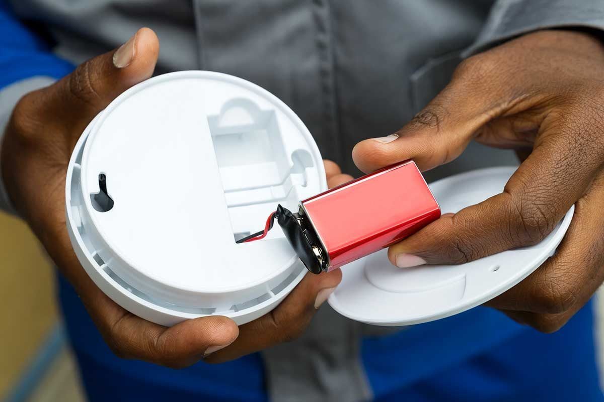 Person showing smoke detector battery.