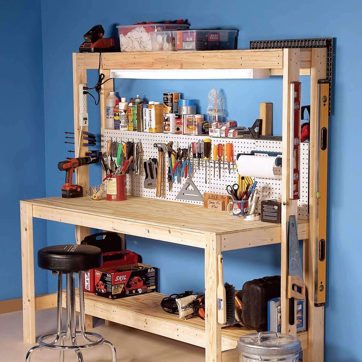 A wooden workbench displays various tools and supplies neatly organized on a pegboard, set against a blue wall in a workshop environment.